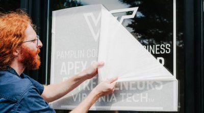 an employee applies a sticky sign to a window